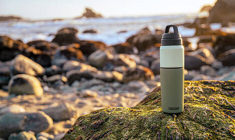A multibev sitting on a rock with the beach in the distance.