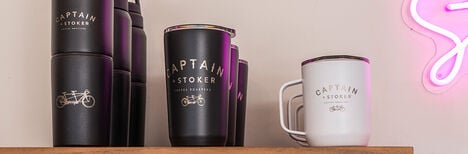 Customized bottles and drinkware sitting on top of a shelf in a coffee shop